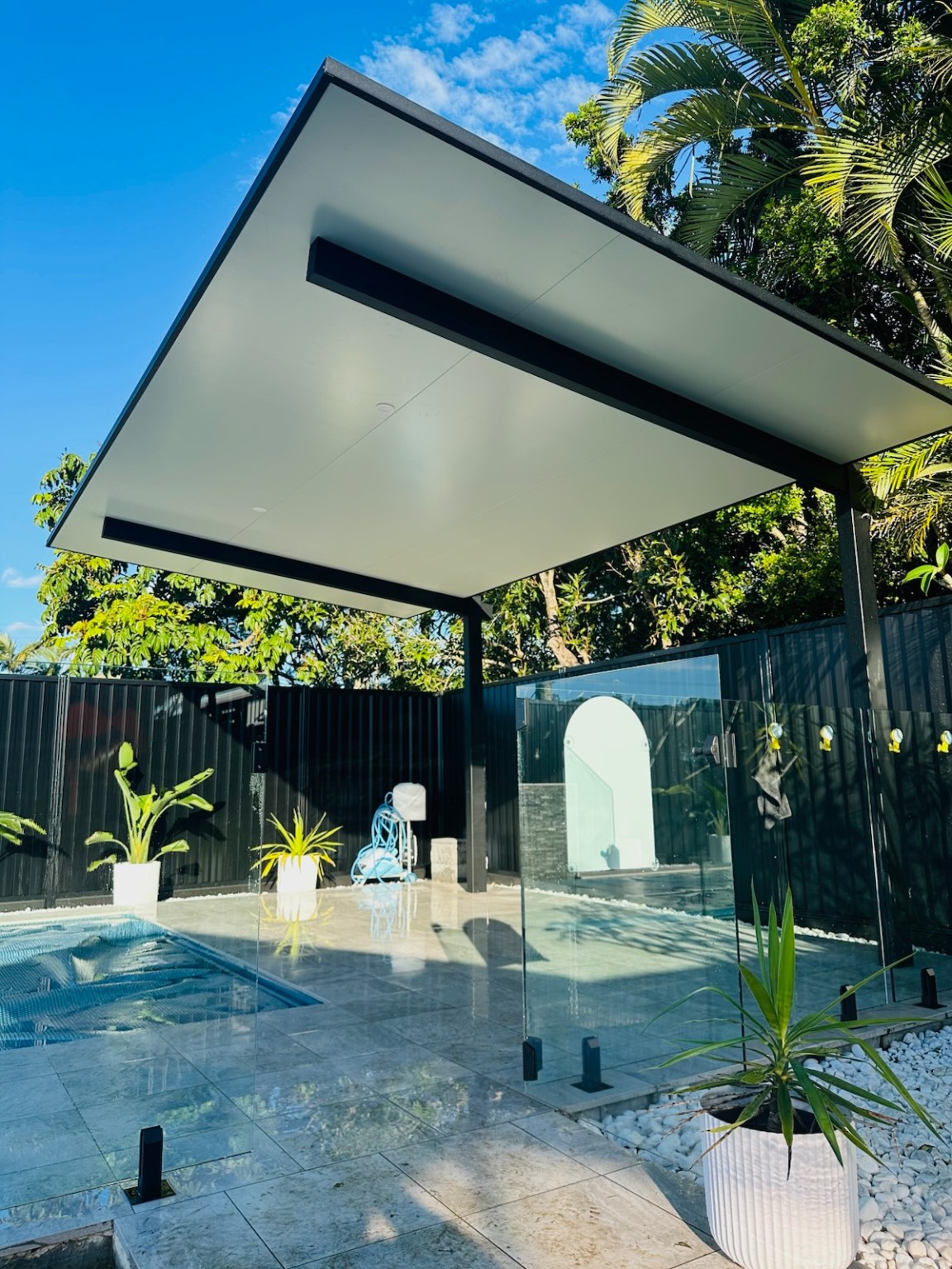 Modern white cantilever pergola beside a pool