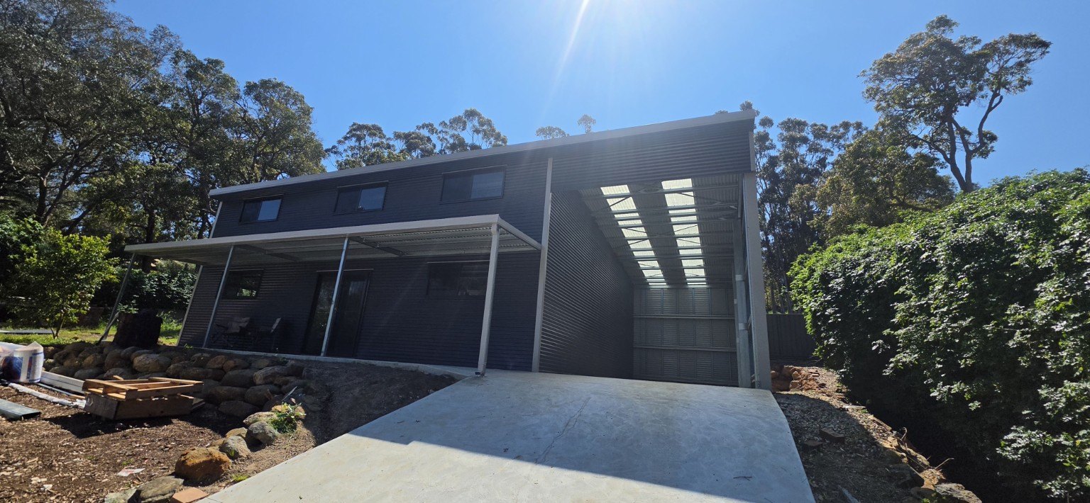 Dark custom shed home with covered veranda and high bay